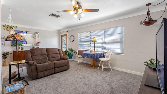 carpeted living area featuring baseboards, visible vents, and a ceiling fan