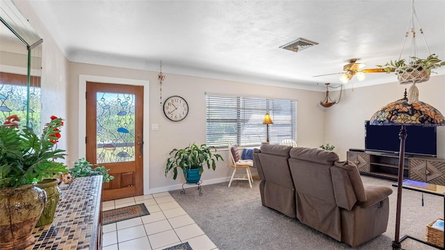 carpeted living area with a ceiling fan, a healthy amount of sunlight, visible vents, and tile patterned floors