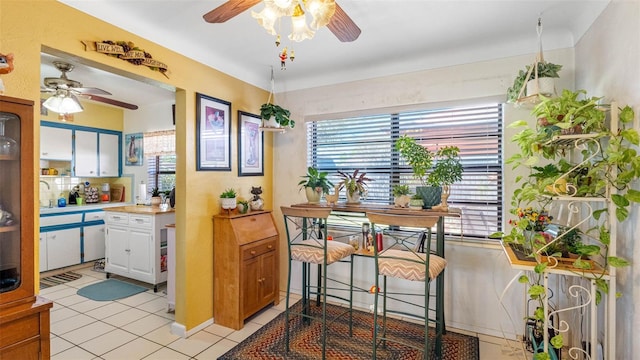 kitchen with light tile patterned floors, light countertops, white cabinetry, and a ceiling fan