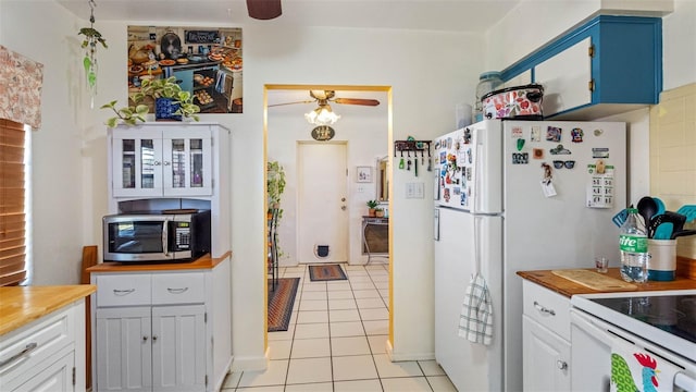 kitchen with white appliances, butcher block counters, light tile patterned floors, and ceiling fan