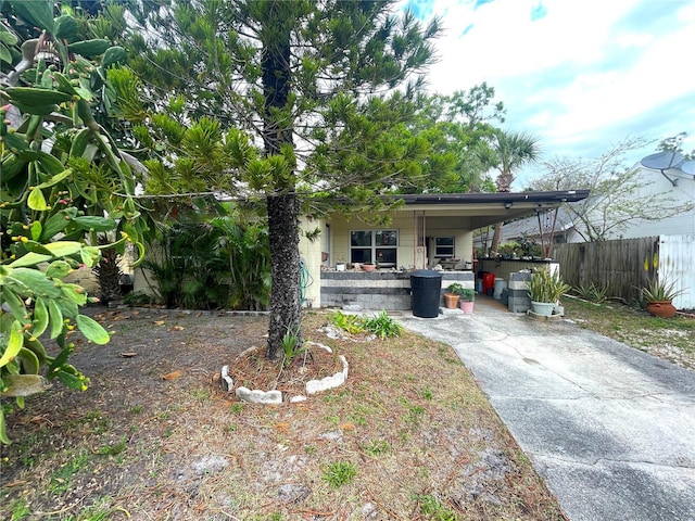 obstructed view of property with a carport, concrete block siding, driveway, and fence