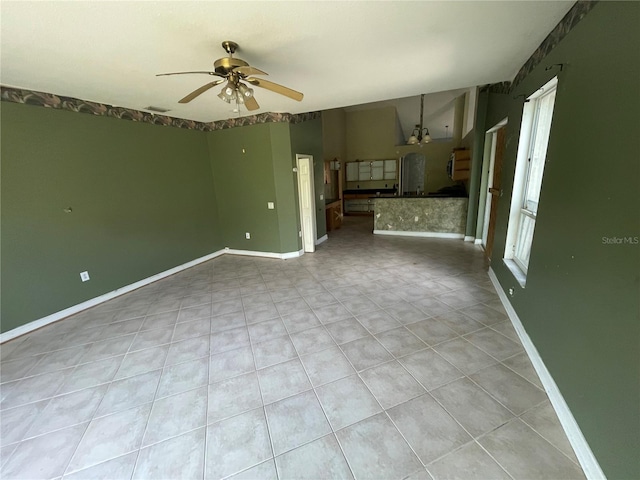 unfurnished living room with ceiling fan, a healthy amount of sunlight, visible vents, and baseboards