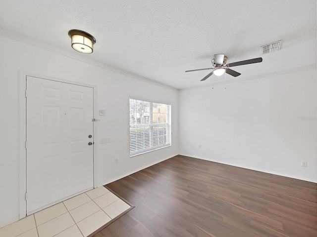 foyer featuring baseboards, visible vents, ceiling fan, wood finished floors, and a textured ceiling