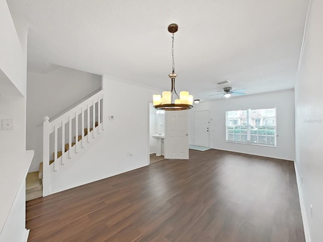 unfurnished living room featuring dark wood-style floors, stairway, ceiling fan with notable chandelier, and visible vents