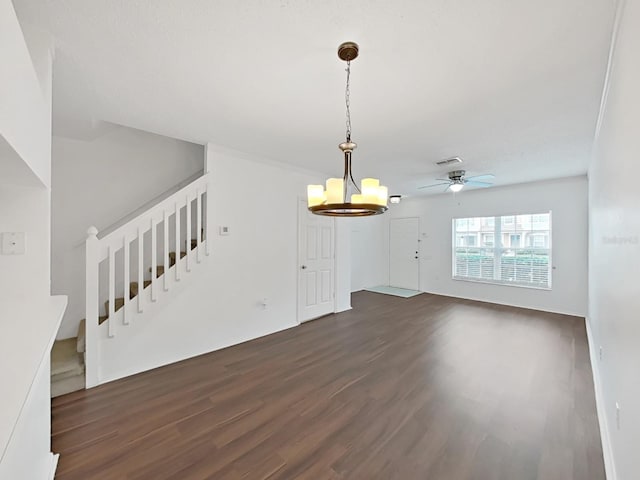 unfurnished living room featuring dark wood-style floors, stairs, visible vents, and ceiling fan with notable chandelier