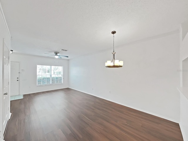 spare room featuring baseboards, visible vents, dark wood-style flooring, a textured ceiling, and ceiling fan with notable chandelier