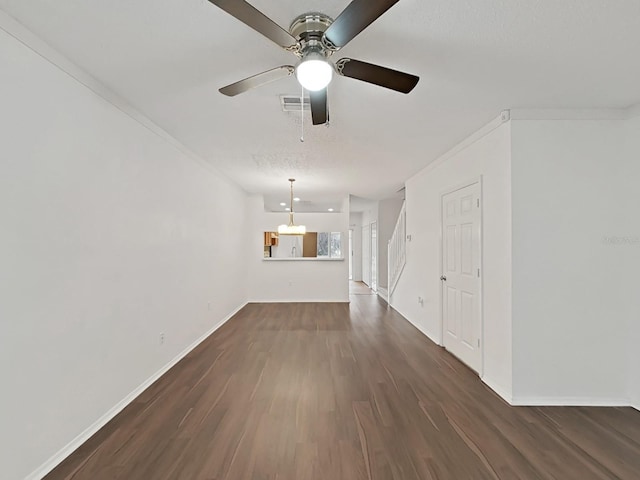 unfurnished living room with ornamental molding, dark wood finished floors, visible vents, and baseboards