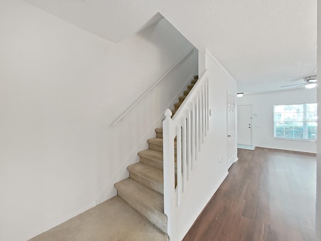 staircase with baseboards, a ceiling fan, and wood finished floors