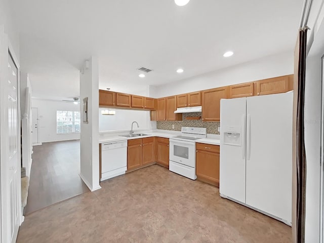 kitchen with light countertops, white appliances, a sink, and under cabinet range hood