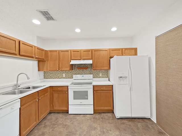 kitchen with white appliances, tasteful backsplash, visible vents, under cabinet range hood, and a sink