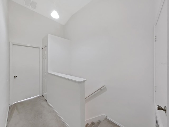 hall with visible vents, concrete floors, vaulted ceiling, and an upstairs landing