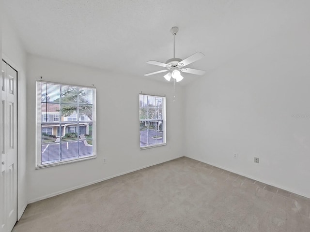 spare room with a ceiling fan and light colored carpet