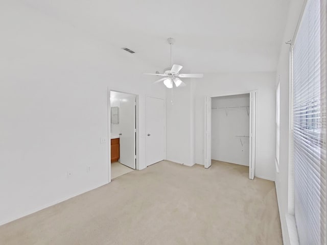 unfurnished bedroom with a ceiling fan, visible vents, light carpet, and ensuite bathroom