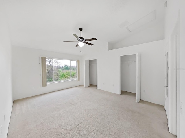 unfurnished bedroom with light carpet, ceiling fan, two closets, and attic access