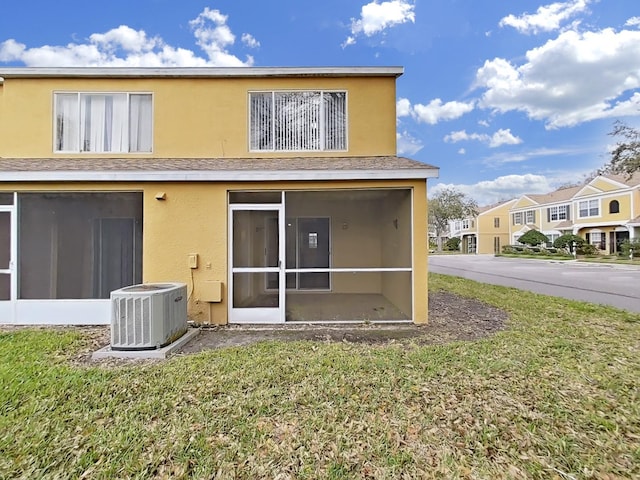 rear view of property featuring a sunroom, a lawn, cooling unit, and stucco siding