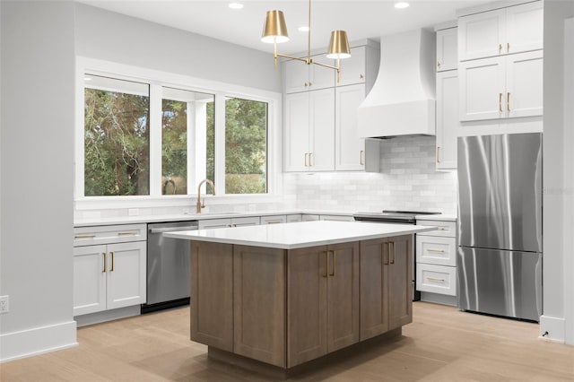 kitchen with stainless steel appliances, light countertops, light wood-style floors, a sink, and premium range hood