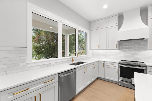 kitchen with premium range hood, a sink, appliances with stainless steel finishes, and a healthy amount of sunlight