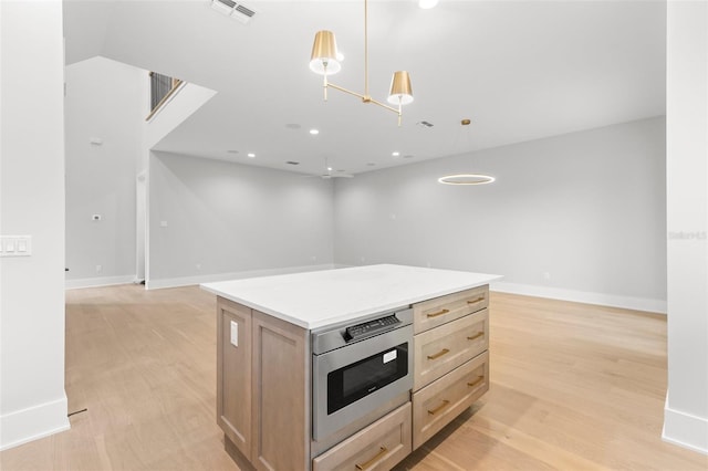 kitchen with stainless steel microwave, visible vents, light wood-style floors, open floor plan, and a kitchen island