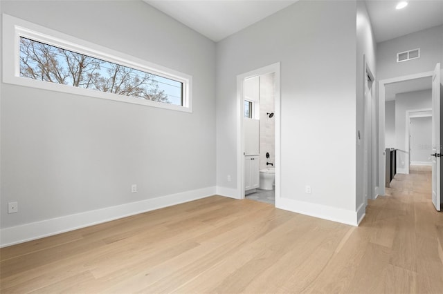 unfurnished bedroom featuring baseboards, connected bathroom, visible vents, and light wood-style floors