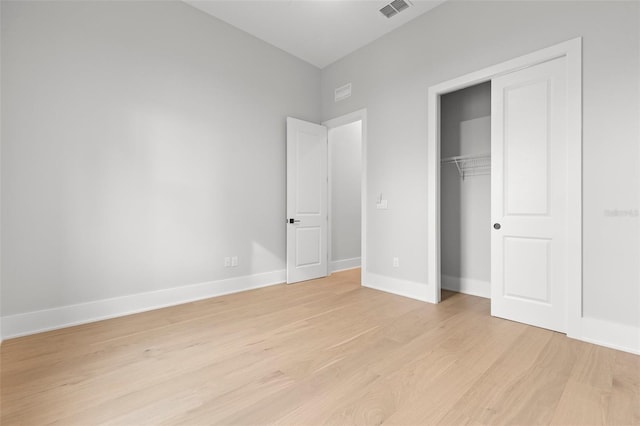 unfurnished bedroom with light wood-type flooring, a closet, visible vents, and baseboards