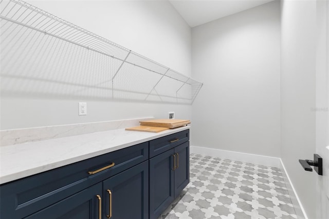 laundry room with light floors, washer hookup, cabinet space, and baseboards