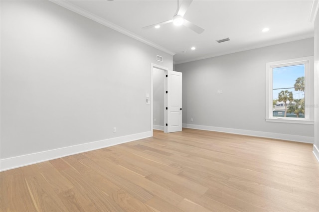 spare room featuring ornamental molding, light wood-style floors, visible vents, and baseboards