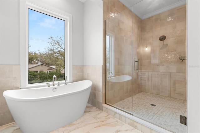 bathroom with marble finish floor, a soaking tub, a shower stall, and tile walls