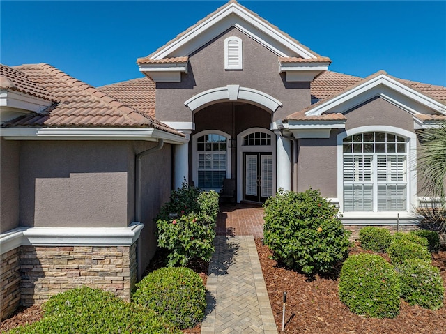 view of front of home with french doors, a tiled roof, and stucco siding