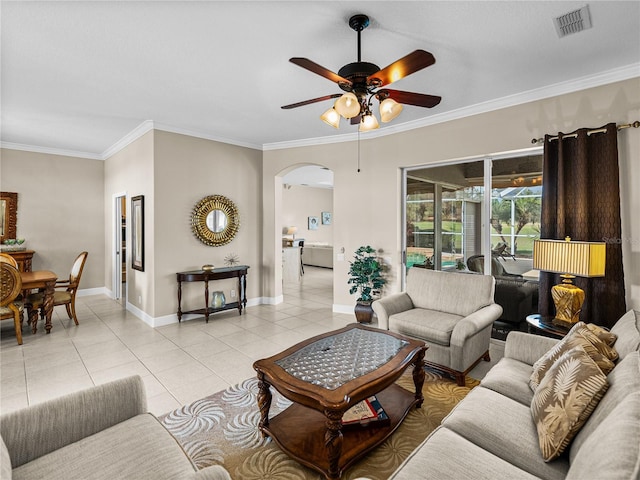 living room with light tile patterned floors, arched walkways, visible vents, baseboards, and crown molding