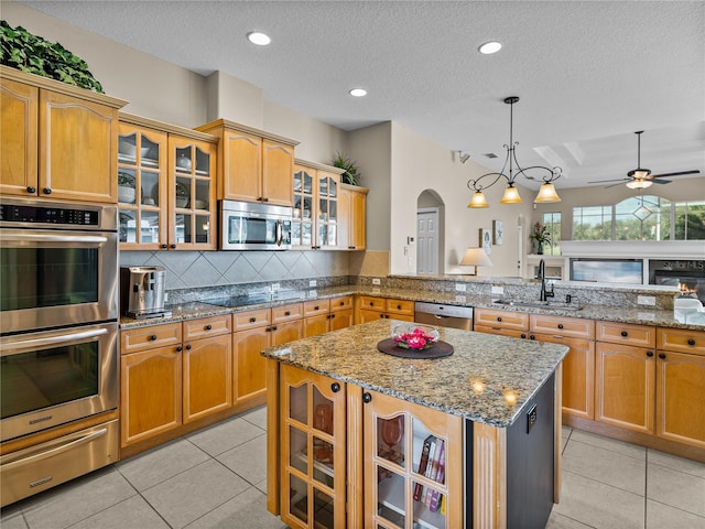 kitchen with a center island, a warming drawer, stainless steel appliances, tasteful backsplash, and a sink