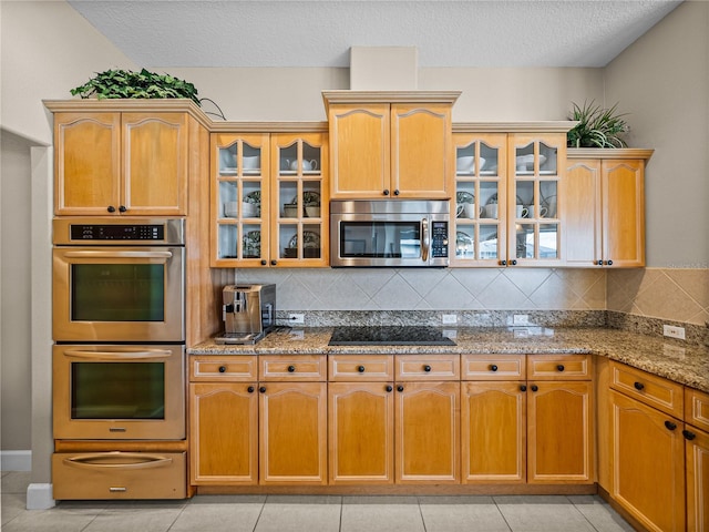 kitchen featuring stainless steel appliances, a warming drawer, backsplash, and light stone counters