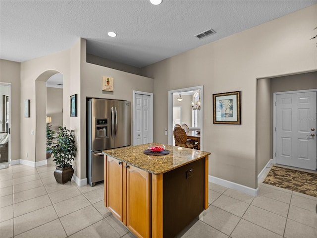 kitchen featuring light tile patterned floors, arched walkways, visible vents, and stainless steel fridge with ice dispenser