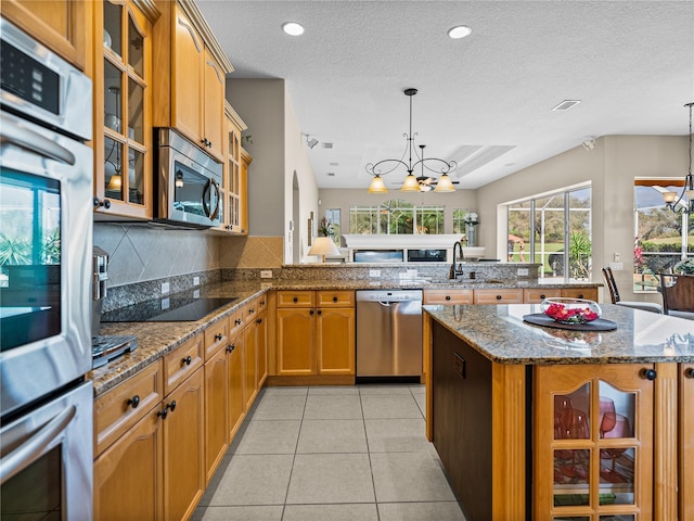 kitchen featuring tasteful backsplash, an inviting chandelier, stainless steel appliances, a sink, and light tile patterned flooring