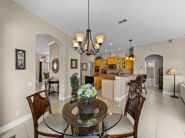 dining space featuring light tile patterned floors, visible vents, arched walkways, and baseboards