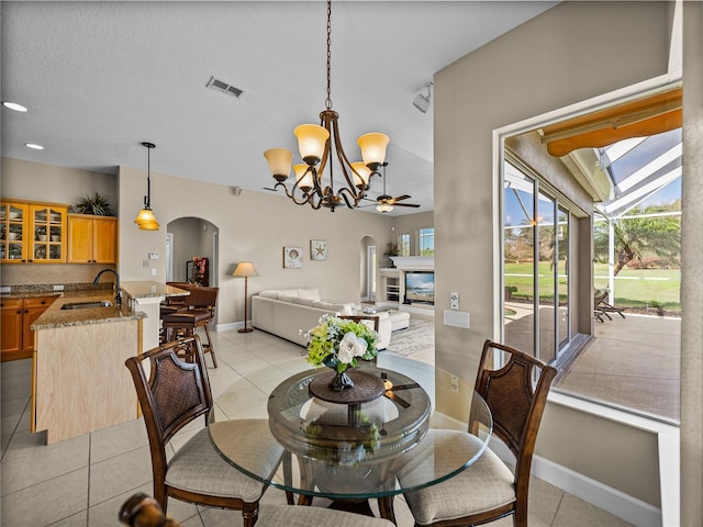 dining room featuring arched walkways, visible vents, a glass covered fireplace, and light tile patterned floors