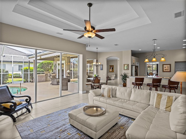 living area with plenty of natural light, visible vents, a tray ceiling, and light tile patterned flooring