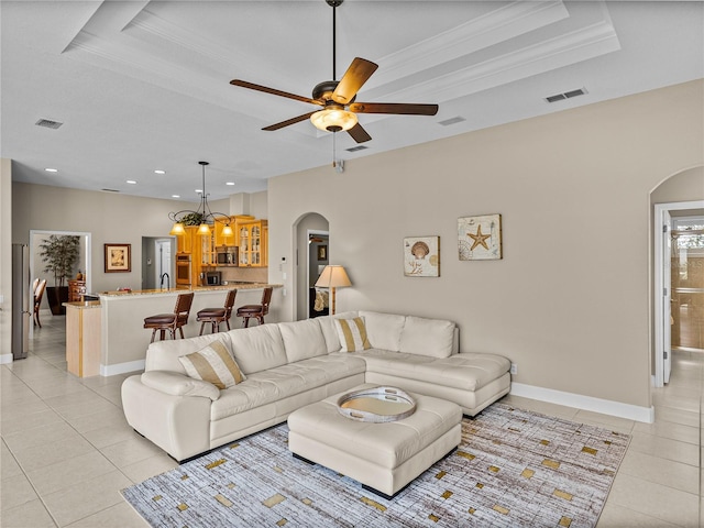 living area with visible vents, arched walkways, and a raised ceiling