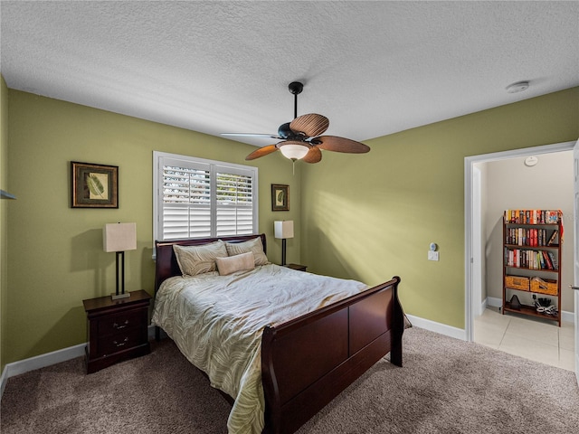 carpeted bedroom featuring a ceiling fan, baseboards, a textured ceiling, and tile patterned floors