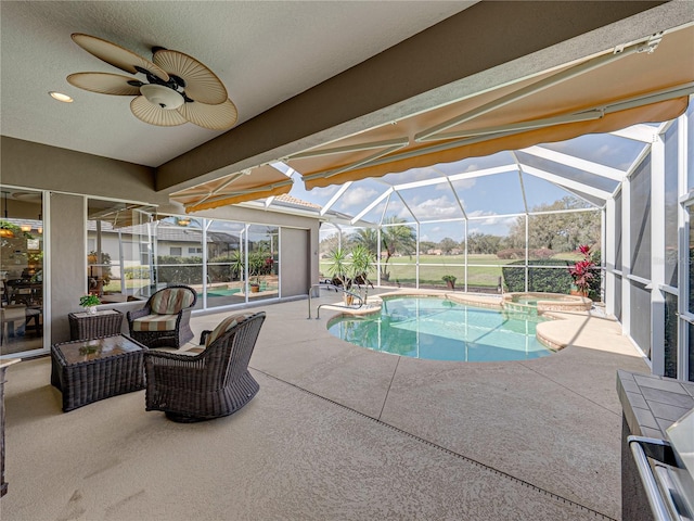 view of pool featuring a patio, glass enclosure, a pool with connected hot tub, and a ceiling fan