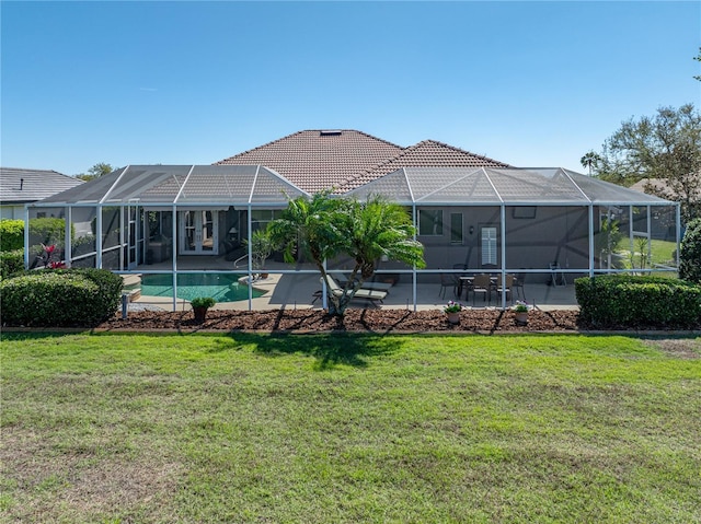 back of house featuring a tiled roof, a lawn, and a patio area