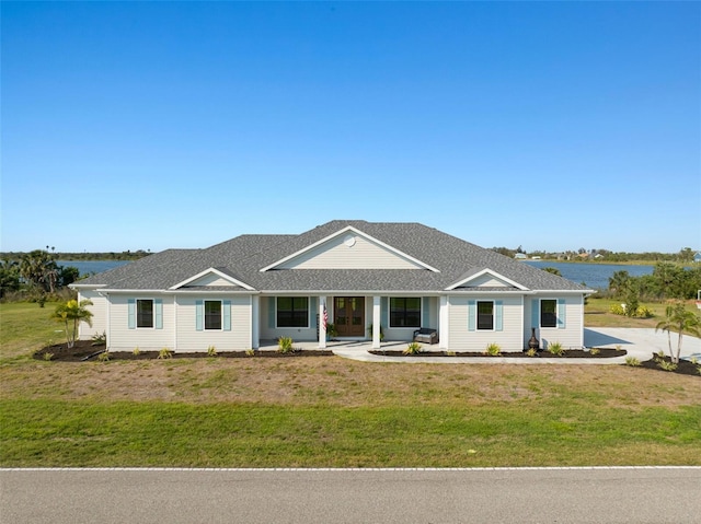 view of front of property featuring a water view, a shingled roof, and a front yard