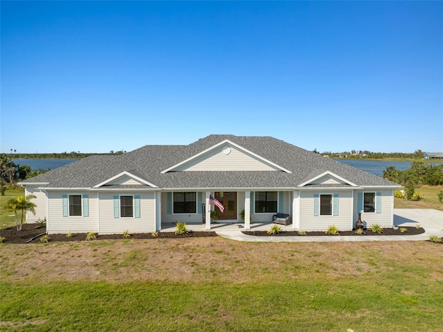 view of front of property featuring a shingled roof, a front yard, and a water view