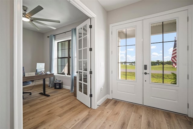 doorway featuring light wood-type flooring, ceiling fan, baseboards, and french doors