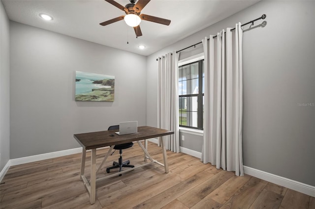 office area with a ceiling fan, light wood-style flooring, and baseboards