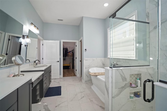 bathroom featuring marble finish floor, a freestanding tub, a shower stall, and visible vents