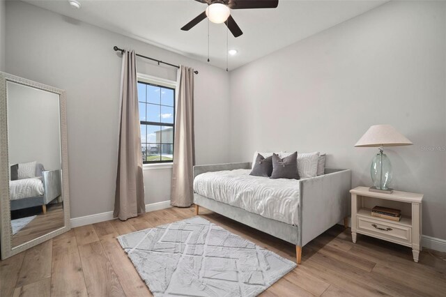 bedroom with a ceiling fan, baseboards, and wood finished floors