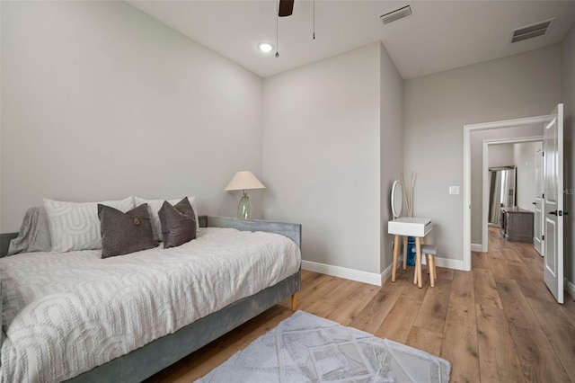 bedroom with a ceiling fan, wood finished floors, visible vents, and baseboards