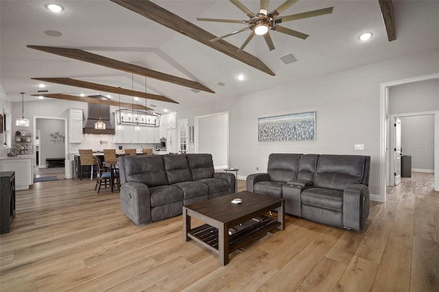 living area featuring visible vents, baseboards, lofted ceiling with beams, light wood-type flooring, and recessed lighting