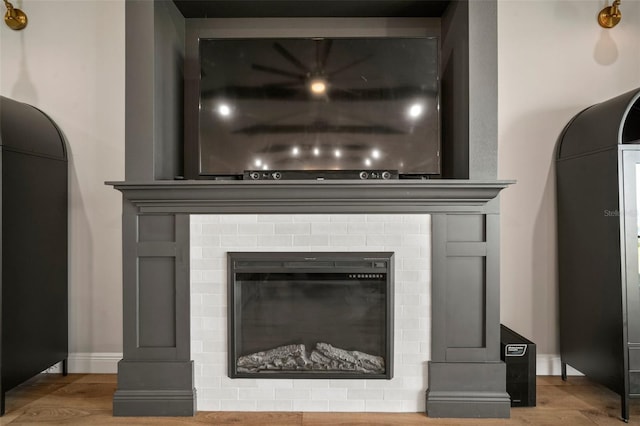 interior details with baseboards, wood finished floors, and a glass covered fireplace