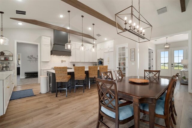 dining room with vaulted ceiling with beams, light wood-style flooring, visible vents, and french doors